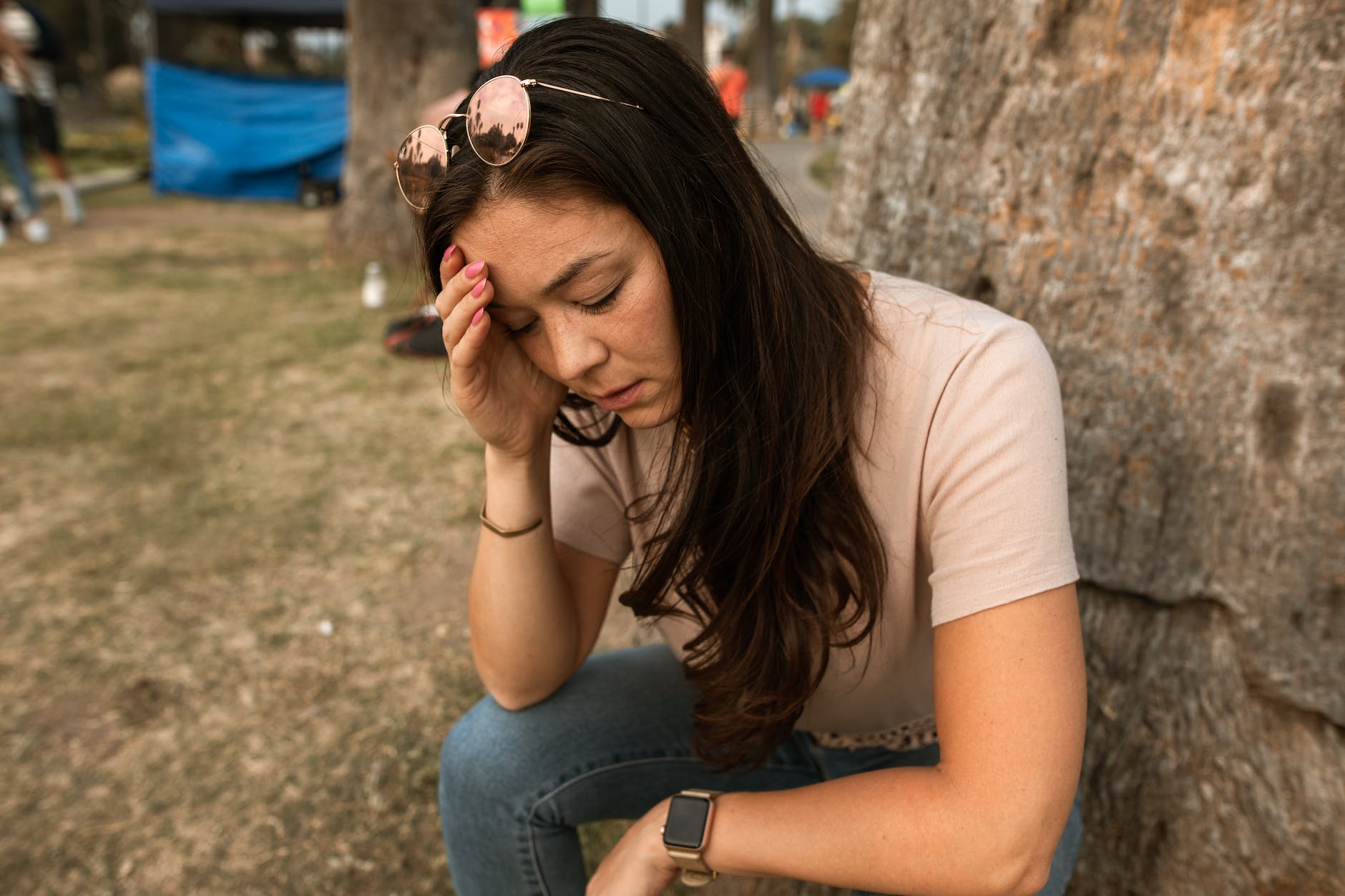 woman with eyes closed touching her forehead